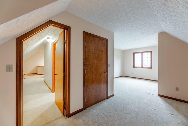 additional living space with a textured ceiling, light carpet, and vaulted ceiling