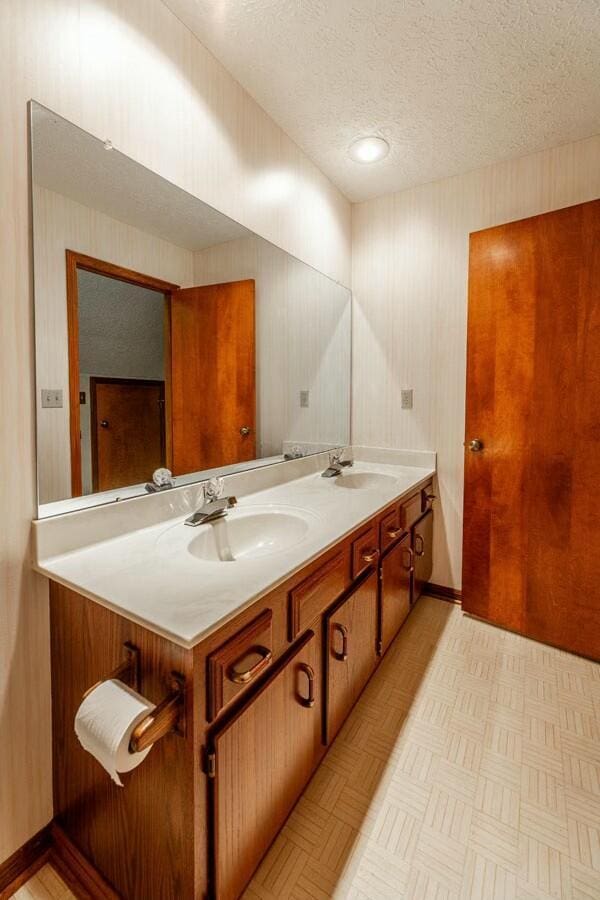 bathroom featuring vanity, a textured ceiling, and parquet flooring