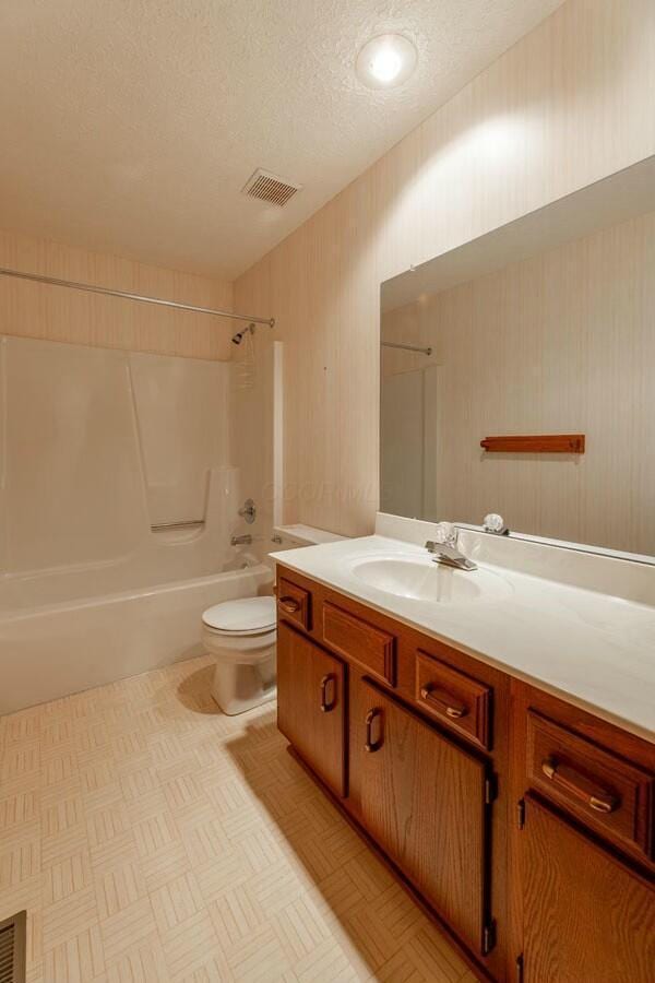 full bathroom with bathing tub / shower combination, vanity, a textured ceiling, and toilet