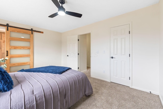 carpeted bedroom featuring a barn door and ceiling fan