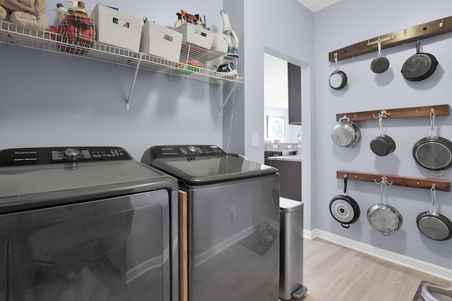 laundry area featuring independent washer and dryer and light hardwood / wood-style flooring