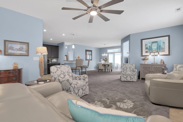 carpeted living room with ceiling fan with notable chandelier