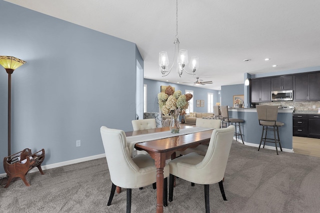 carpeted dining area featuring ceiling fan with notable chandelier