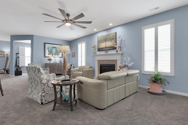 carpeted living room with ceiling fan and a tile fireplace