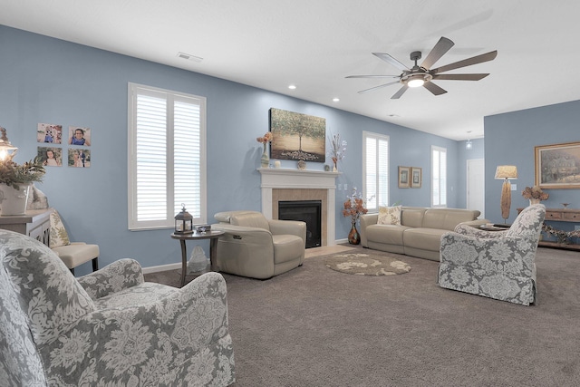 living room featuring carpet flooring, ceiling fan, a healthy amount of sunlight, and a tiled fireplace