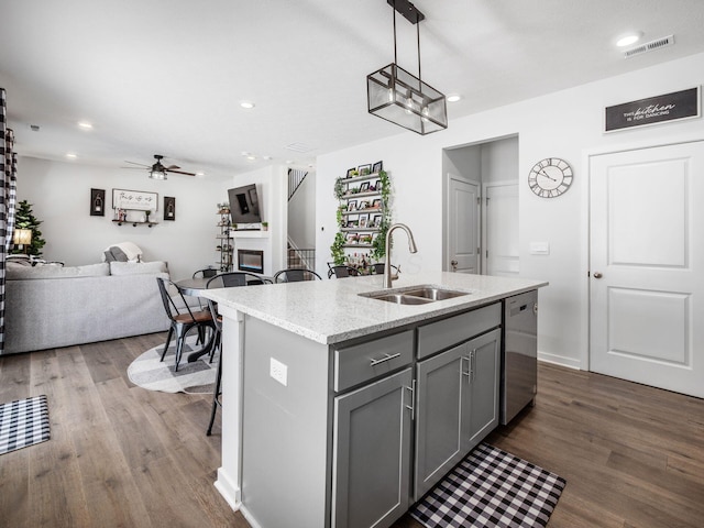 kitchen featuring gray cabinets, ceiling fan, a kitchen island with sink, stainless steel dishwasher, and sink