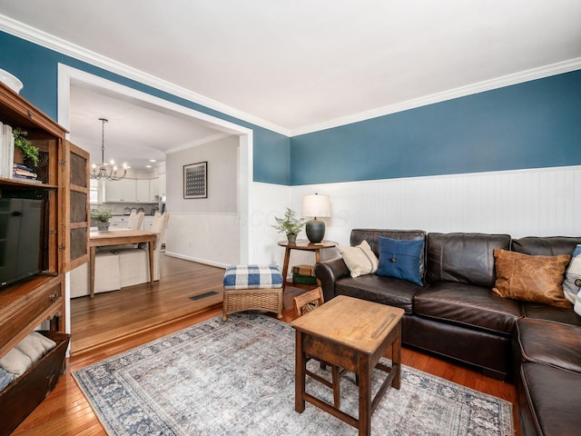 living room featuring wood-type flooring, an inviting chandelier, and ornamental molding