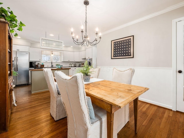 dining area featuring a chandelier, sink, dark wood-type flooring, and ornamental molding