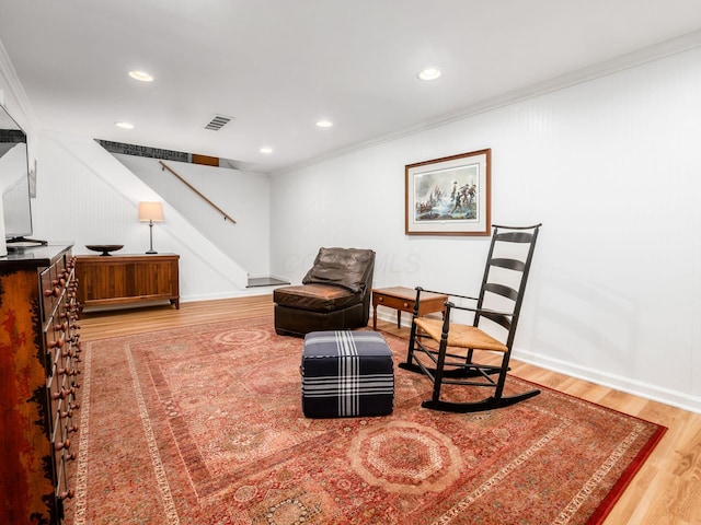 living area with hardwood / wood-style floors and ornamental molding