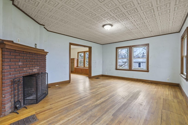 unfurnished living room with a fireplace, a healthy amount of sunlight, and light wood-type flooring