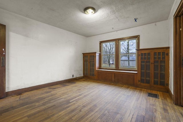 empty room featuring a textured ceiling and dark hardwood / wood-style floors