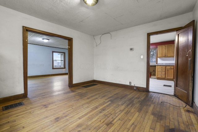 unfurnished room with wood-type flooring and a textured ceiling