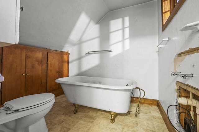 bathroom with a tub to relax in, vaulted ceiling, and toilet