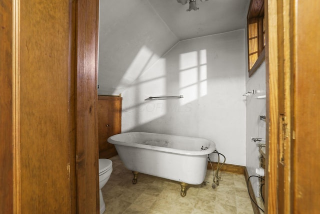 bathroom featuring a tub, vaulted ceiling, and toilet