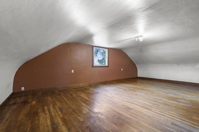 bonus room featuring a textured ceiling, vaulted ceiling, and dark wood-type flooring