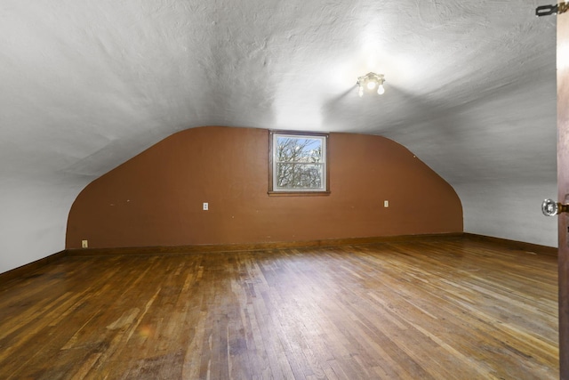 bonus room with a textured ceiling, wood-type flooring, and lofted ceiling