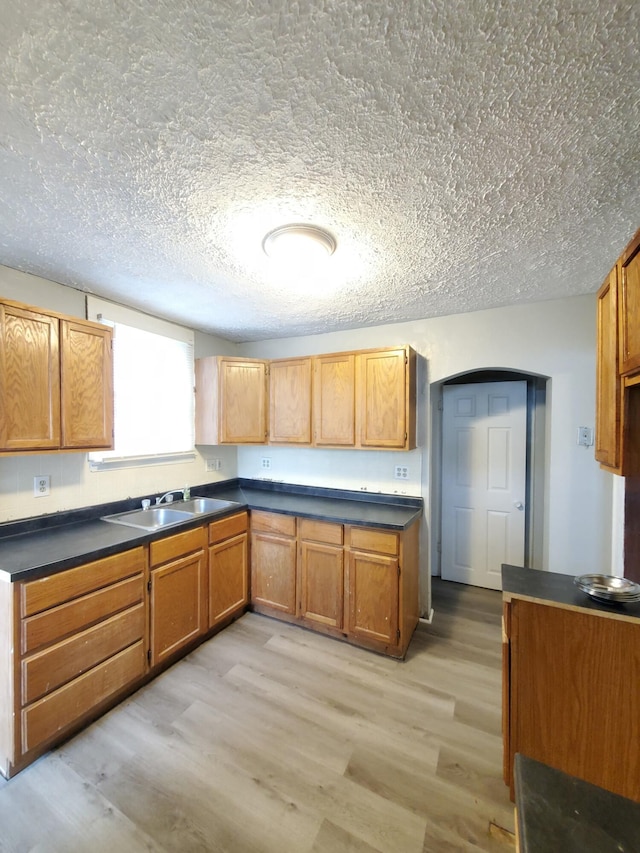 kitchen featuring a textured ceiling, light hardwood / wood-style floors, and sink