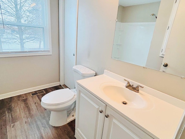 bathroom featuring visible vents, baseboards, toilet, wood finished floors, and vanity