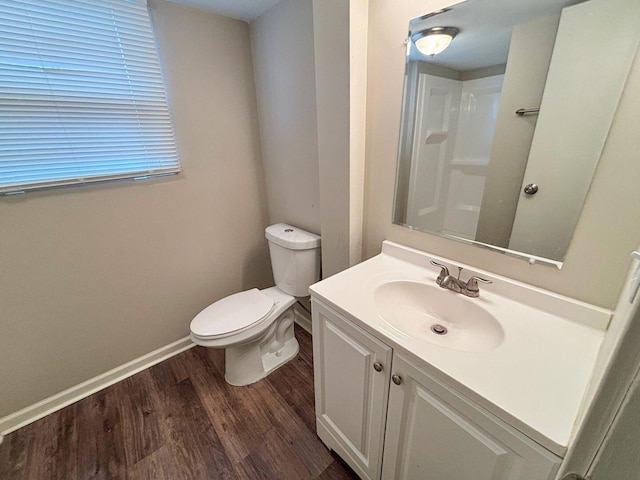 bathroom featuring toilet, vanity, baseboards, and wood finished floors