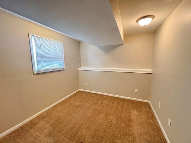 spare room with baseboards and carpet floors