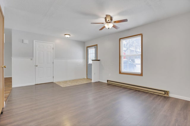 empty room featuring hardwood / wood-style flooring, baseboard heating, and ceiling fan