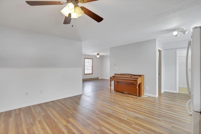 spare room featuring ceiling fan, baseboard heating, and light hardwood / wood-style flooring