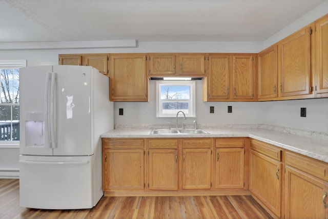 kitchen featuring white refrigerator with ice dispenser, light hardwood / wood-style floors, plenty of natural light, and sink