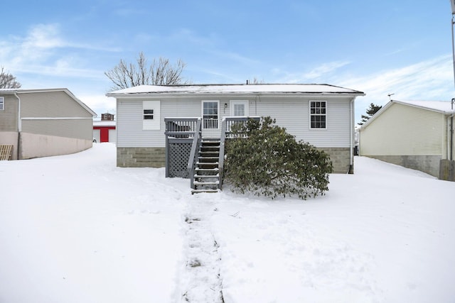 snow covered back of property featuring a wooden deck