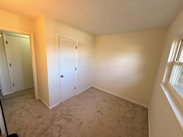 unfurnished bedroom featuring light carpet and a closet