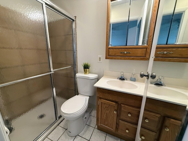 bathroom featuring tile patterned floors, vanity, a shower with shower door, and toilet