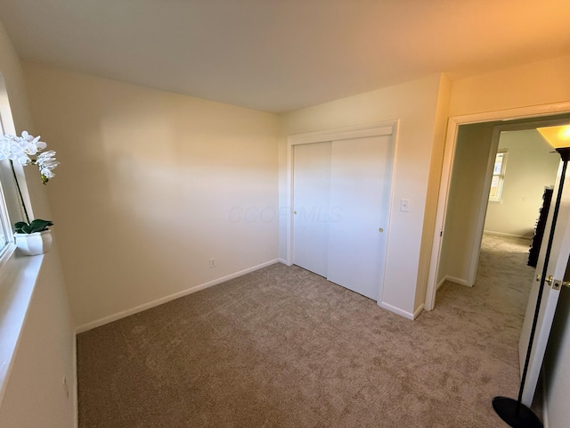 unfurnished bedroom with light colored carpet and a closet