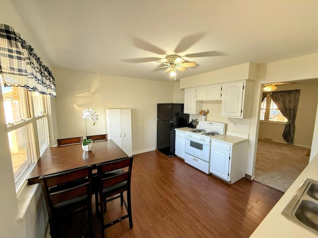 kitchen featuring black fridge, sink, dark hardwood / wood-style floors, gas range gas stove, and white cabinetry