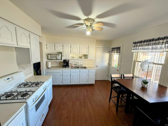 kitchen with white appliances, white cabinets, sink, ceiling fan, and dark hardwood / wood-style flooring