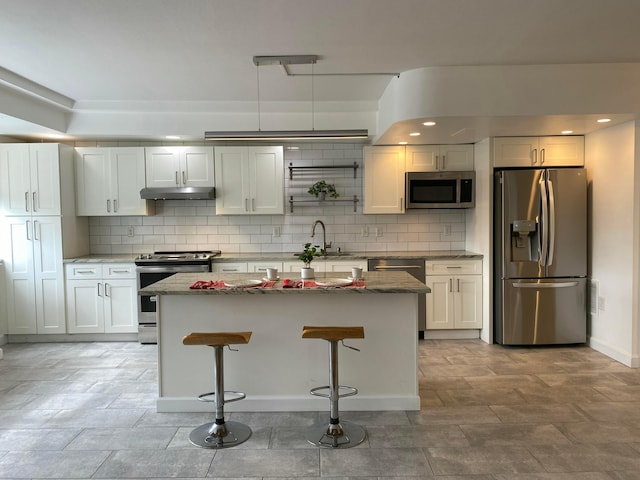 kitchen with pendant lighting, sink, white cabinets, a kitchen breakfast bar, and stainless steel appliances