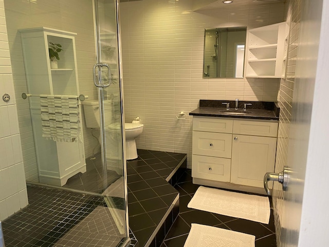 bathroom featuring tile walls, tile patterned flooring, vanity, walk in shower, and toilet