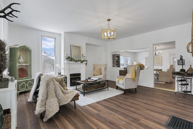 living room featuring a chandelier, dark hardwood / wood-style floors, plenty of natural light, and a fireplace