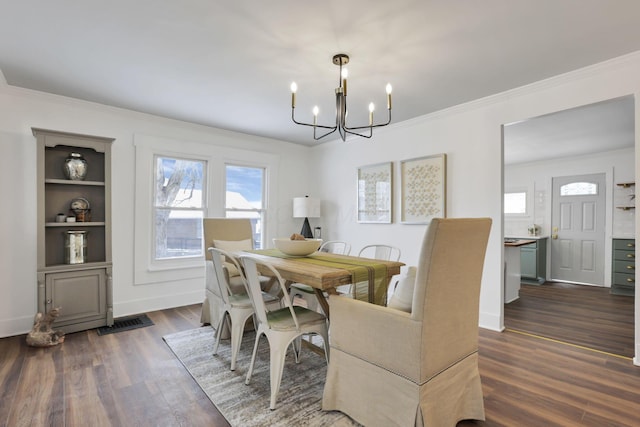 dining area featuring dark wood-type flooring, a chandelier, and ornamental molding