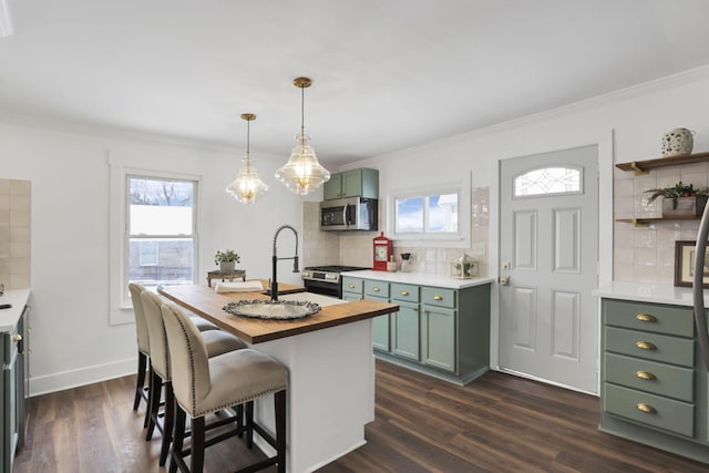 kitchen featuring crown molding, decorative backsplash, an island with sink, appliances with stainless steel finishes, and dark hardwood / wood-style flooring