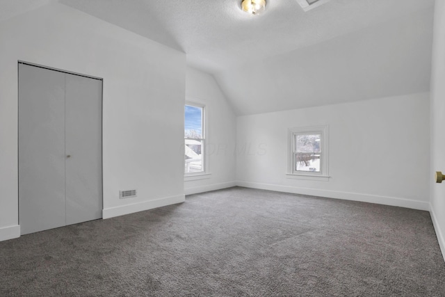 additional living space featuring lofted ceiling and dark colored carpet