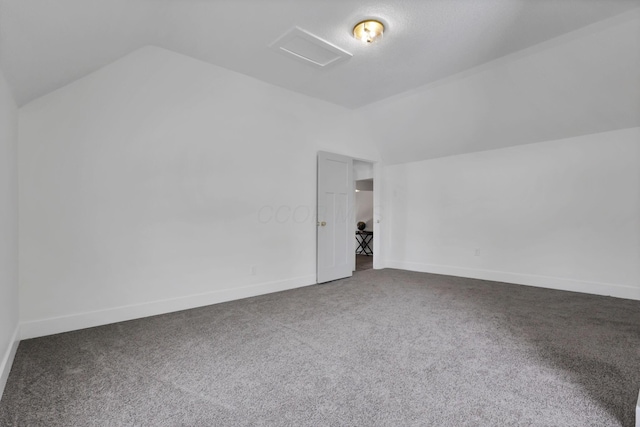 additional living space featuring lofted ceiling and dark colored carpet