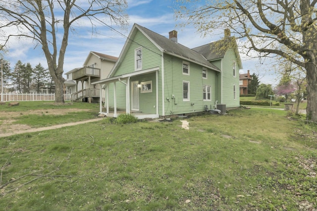 view of property exterior featuring a chimney, a lawn, fence, and central AC