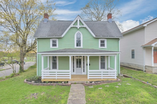 victorian house featuring a porch, a shingled roof, and a front yard