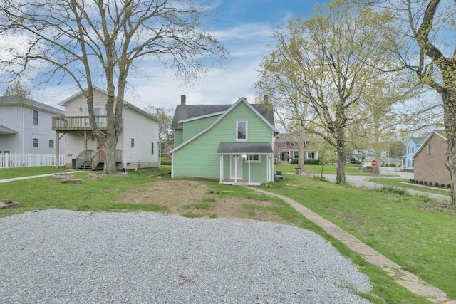 rear view of property featuring a yard, a deck, and a chimney