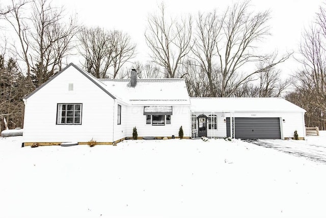 snow covered back of property featuring a garage