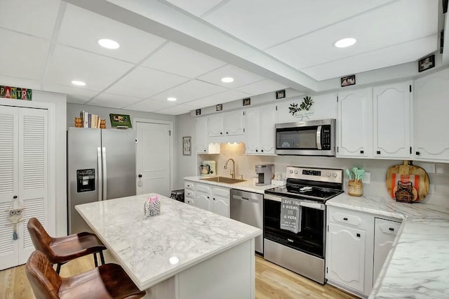 kitchen featuring sink, white cabinets, a kitchen breakfast bar, stainless steel appliances, and light hardwood / wood-style flooring