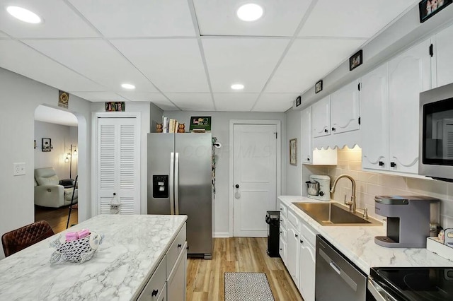 kitchen featuring sink, white cabinetry, appliances with stainless steel finishes, light hardwood / wood-style floors, and backsplash