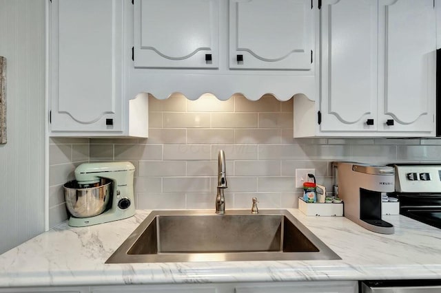 kitchen featuring sink, backsplash, stainless steel dishwasher, and white cabinets