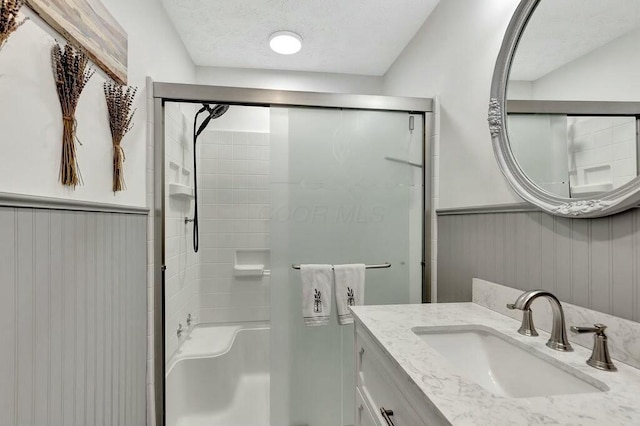 bathroom featuring walk in shower, vanity, and a textured ceiling