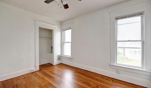 unfurnished bedroom with a textured ceiling, a closet, light hardwood / wood-style floors, and ceiling fan