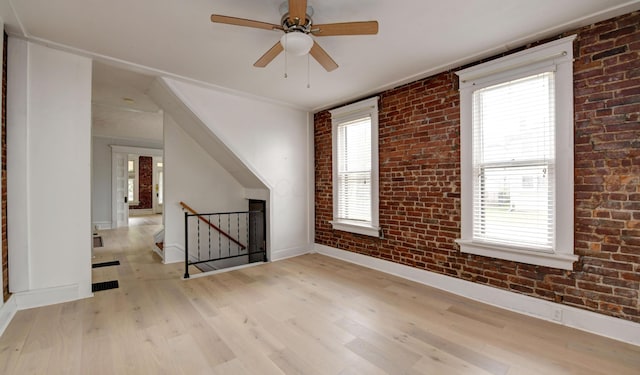 additional living space with light hardwood / wood-style flooring, ceiling fan, plenty of natural light, and brick wall